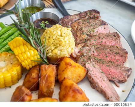 Ribeye beef steak medium to well done grilled served with corn, pototoes and asparagus Ribeye beef steak medium to well done grilled served with corn, pototoes and asparagus 60015684