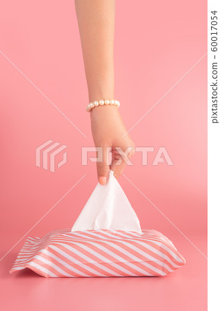 woman pull the tissue paper out of the tissue box isolated on pink background, vertical. sanitation and hygiene facility concept 60017054