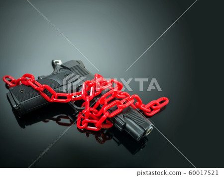 reform gun control concept. red chain around handgun on black mirror with spotlight shine to the gun 60017521