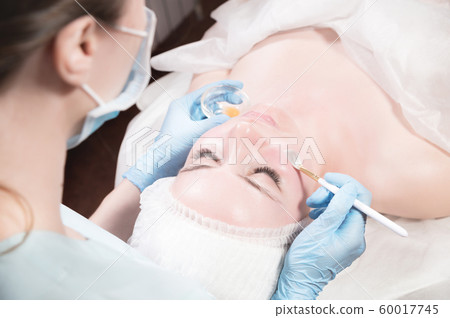 Girl beautician applies a brush to rejuvenate a mask on the face of an attractive girl in a spa salon. The concept of self-care and rejuvenation Girl beautician applies a brush to rejuvenate a mask on the face of an attractive girl in a spa salon. The concept of self-care and rejuvenation 60017745