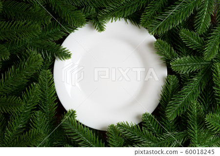 Top view of white plate surrounded with fir tree Top view of white plate surrounded with fir tree 60018245