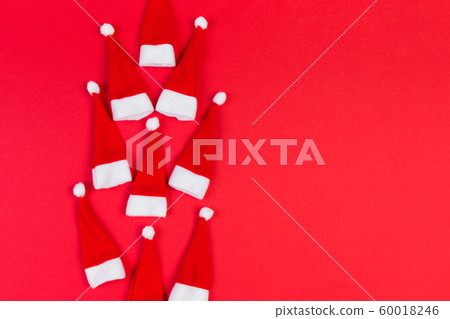 Top view of red Santa hats on colorful background. 60018246