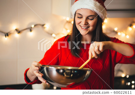 Happy woman in Santa hat cooking Christmas cookies Happy woman in Santa hat cooking Christmas cookies 60022611
