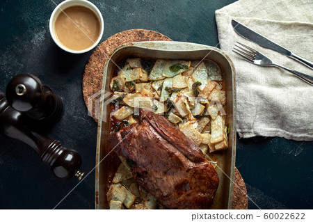 Roasted pork neck with baked potatoes and herbs on a tray on the black background Roasted pork neck with baked potatoes and herbs on a tray on the black background 60022622