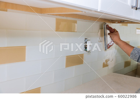 Tilers filling the space between tiles using rubber trowel grouting ceramic tiles. Tilers filling the space between tiles using rubber trowel grouting ceramic tiles. 60022986