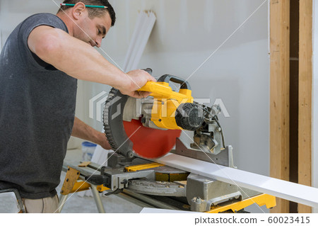 Man cut the wooden molding with circular saw Man cut the wooden molding with circular saw 60023415