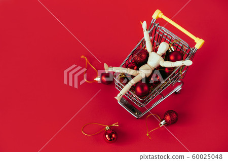 Figurine of a wooden man in a basket for shopping Figurine of a wooden man in a basket for shopping 60025048