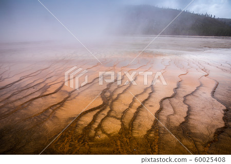 Smoke covered orange pond of geyser basin. Smoke covered orange pond of geyser basin. 60025408