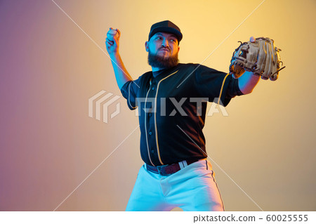 Baseball player, pitcher in a black uniform practicing on gradient background in neon light 60025555