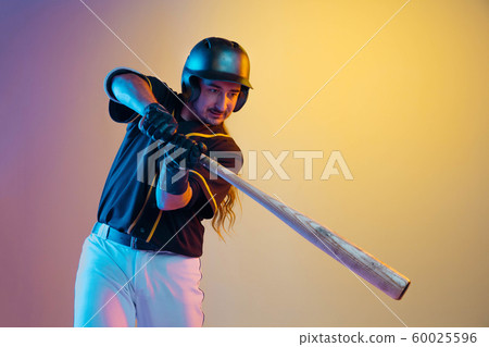 Baseball player, pitcher in a black uniform practicing on gradient background in neon light 60025596