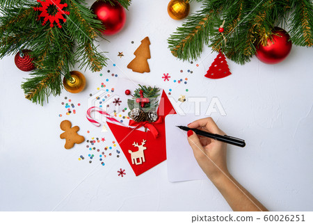 Photo of red envelope, cookies, hands with pen, branches of spruce Christmas decorations Photo of red envelope, cookies, hands with pen, branches of spruce Christmas decorations 60026251