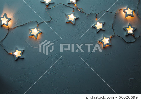Burning Christmas garland on empty blue table Burning Christmas garland on empty blue table 60026699