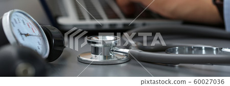 Stethoscope head and manometer lying on table closeup Stethoscope head and manometer lying on table closeup 60027036