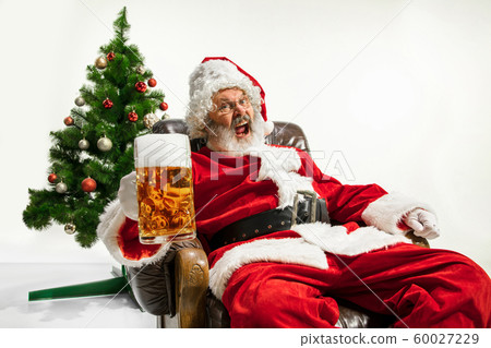 Santa Claus drinking beer near Christmas tree, congratulating of New Year 2020 60027229