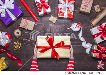 Woman holding Christmas present in gold gift box 60028939