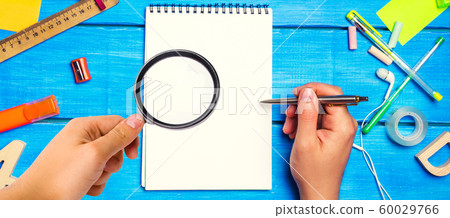 school concept, accessories. the schoolboy points to a notepad. hand with magnifying glass. new ideas, homework solution. back to school. place for text. copyspace school concept, accessories. the schoolboy points to a notepad. hand with magnifying glass. new ideas, homework solution. back to school. place for text. copyspace 60029766