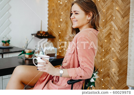 Woman holds a cup of coffee in the morning in Christmas kitchen 60029978