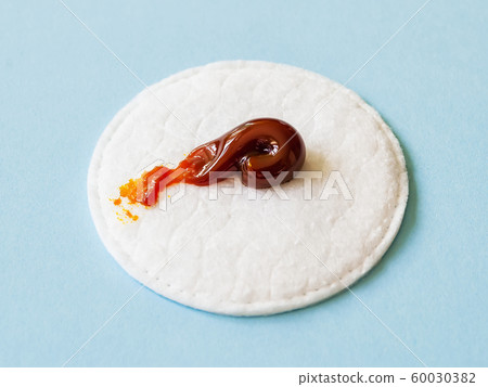 An iodine ointment on a cotton pad over a blue background. For wounds and for skin disinfection. 60030382