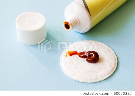 Some iodine ointment on a cotton pad near an open tube. Salve for wound disinfection. 60030383