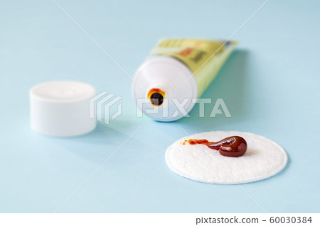 An iodine ointment on a cotton pad near an open tube. Salve for wound disinfection. 60030384