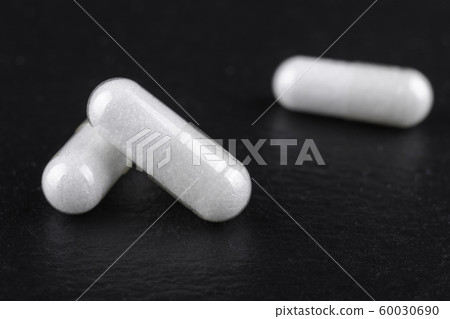 white capsules of nutritional supplement msm, sulfur on black background white capsules of nutritional supplement msm, sulfur on black background 60030690