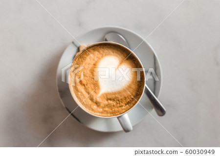One cup of cappuccino with latte art on marble white table, white ceramic cup, top view. Cafe culture. 60030949