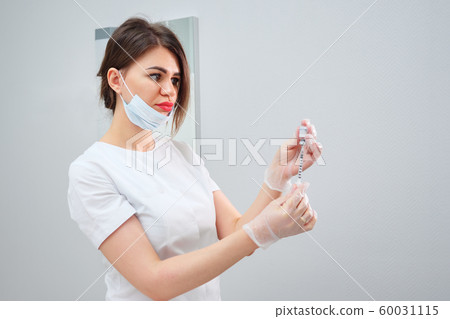 cosmetologist holds syringe filled with gel medication 60031115