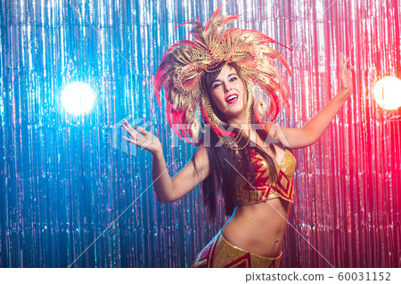 Cabaret, dancer and holidays concept - Cute young girl in bright colorful carnival costume on dark background 60031152