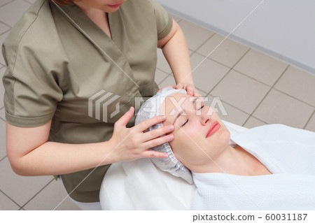 masseuse does face massage to woman in medical clinic 60031187