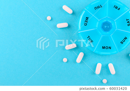 different medicines for one week and a pills box on blue background with copy space 60031420