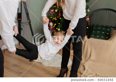 Happy dad and mom swing their daughter in their Happy dad and mom swing their daughter in their 60031848