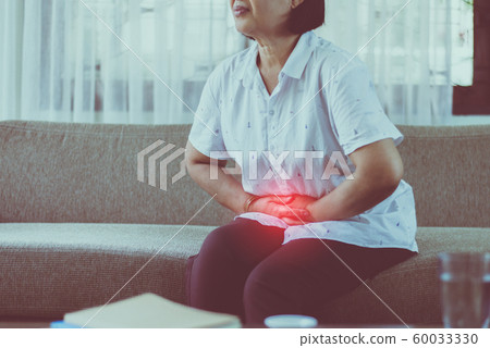 Elderly asian woman having stomachache while sitting on sofa at home,Senior female suffering from abdominal pain Elderly asian woman having stomachache while sitting on sofa at home,Senior female suffering from abdominal pain 60033330