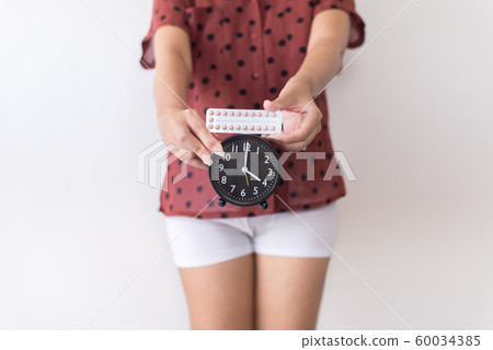 Woman hands holding birth control pill and clock,Concept for contraceptive,Copy space for text on white background Woman hands holding birth control pill and clock,Concept for contraceptive,Copy space for text on white background 60034385