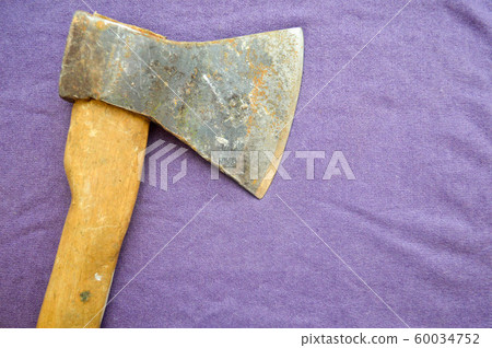 Old, rusty ax with a wooden handle on a  60034752