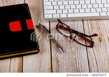 Office supplies, glasses and black notepad on the 60034875