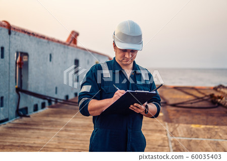 Deck Officer on deck of offshore vessel or ship , wearing PPE personal protective equipment. He 60035403
