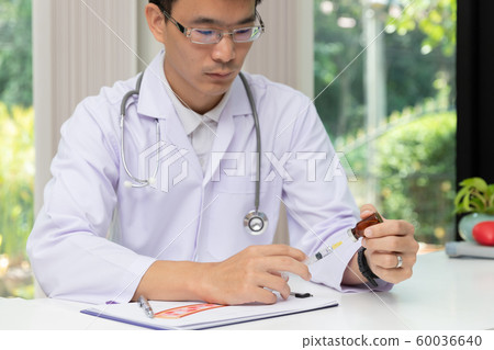 Doctor holding injection needle and vaccine bottle 60036640