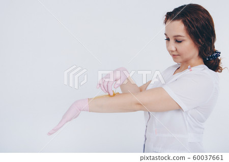 Hands in rubber gloves close-up. doctor puts wax, honey. medic is preparing for depilation. Concept of medicine, medical instruments, health care, beauty industry, hair removal, natural material 60037661