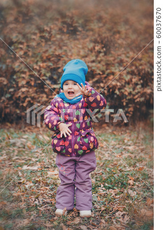 a small child with mother in a warm suit walks in the woods. autumn park. The concept of children's fashion, accessories, outdoor walks a small child with mother in a warm suit walks in the woods. autumn park. The concept of children's fashion, accessories, outdoor walks 60037670