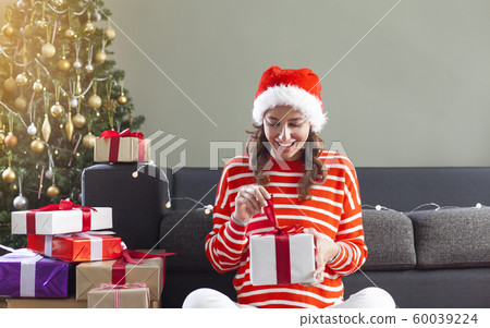 Woman opening Christmas gift Woman opening Christmas gift 60039224