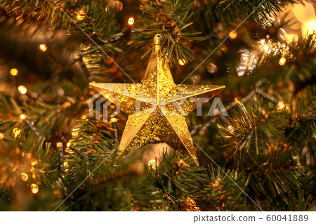 Christmas tree with gold bauble ornaments. Decorated Christmas tree closeup. Balls and illuminated garland with flashlights. New Year baubles macro photo with bokeh. Winter holiday light decoration Christmas tree with gold bauble ornaments. Decorated Christmas tree closeup. Balls and illuminated garland with flashlights. New Year baubles macro photo with bokeh. Winter holiday light decoration 60041889