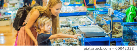 Mom and son in the Korean market. Raw seafood at Noryangjin Fisheries Wholesale Market in Seoul Mom and son in the Korean market. Raw seafood at Noryangjin Fisheries Wholesale Market in Seoul 60042338