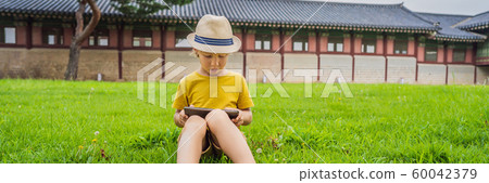 Young boy outdoors on the grass at backyard using his tablet computer. Educating and playing BANNER 60042379