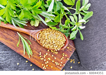 Fenugreek in spoon with herbs on board top 60044351