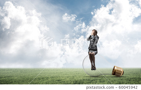 Young woman sitting on big light bulb Young woman sitting on big light bulb 60045942