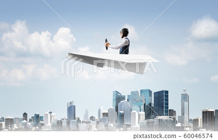 Aviator driving paper plane above business center Aviator driving paper plane above business center 60046574