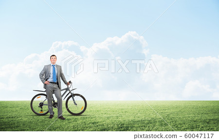 Smiling businessman with bicycle outdoors 60047117