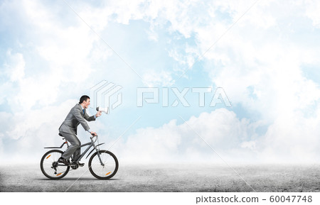 Businessman with megaphone on bike Businessman with megaphone on bike 60047748