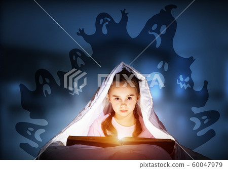 Scared kid with reading book under blanket Scared kid with reading book under blanket 60047979