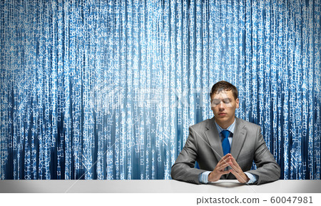 Young serious man folded hands and sitting at desk 60047981